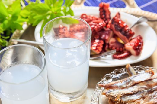 Glasses of ouzo with octopus, small fish and traditional Greek seafood meze.
