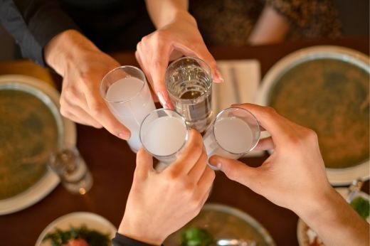 Friends raising glasses of tsipouro and ouzo around a Greek meze table.